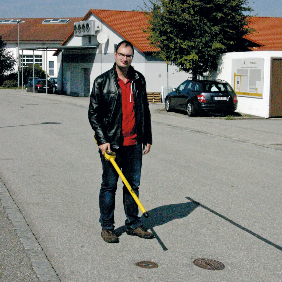 Mann nutzt das gelbe proNIVO Magnetsuchgerät zur Ortung eines Metalldeckels auf einer Straße.