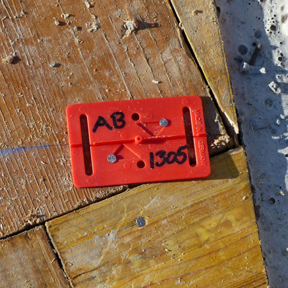 Rote Meterriss-Plakette auf einer Holzschalung befestigt und mit Höhenangabe beschriftet.