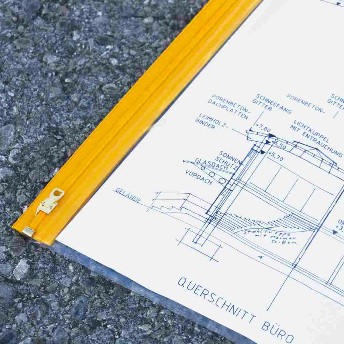 Große Planschutztasche DIN A1 mit gelbem Reißverschluss und eingelegtem Bauplan auf Asphalt.
