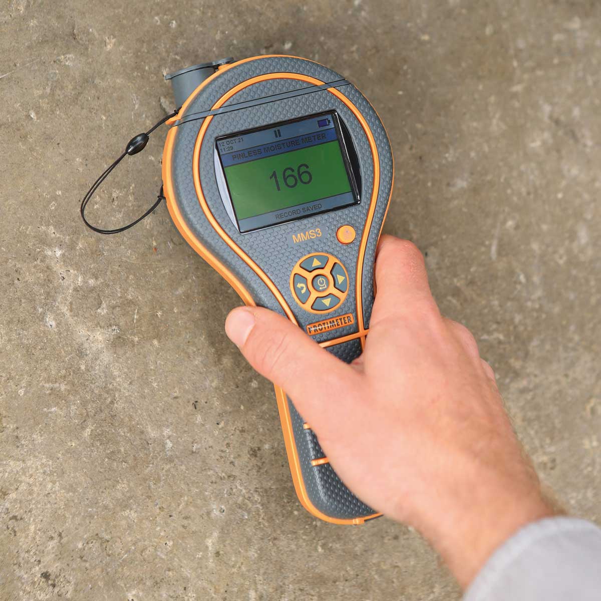Hand hält das Protimeter MMS3 zur zerstörungsfreien Feuchtemessung auf einen Betonboden.