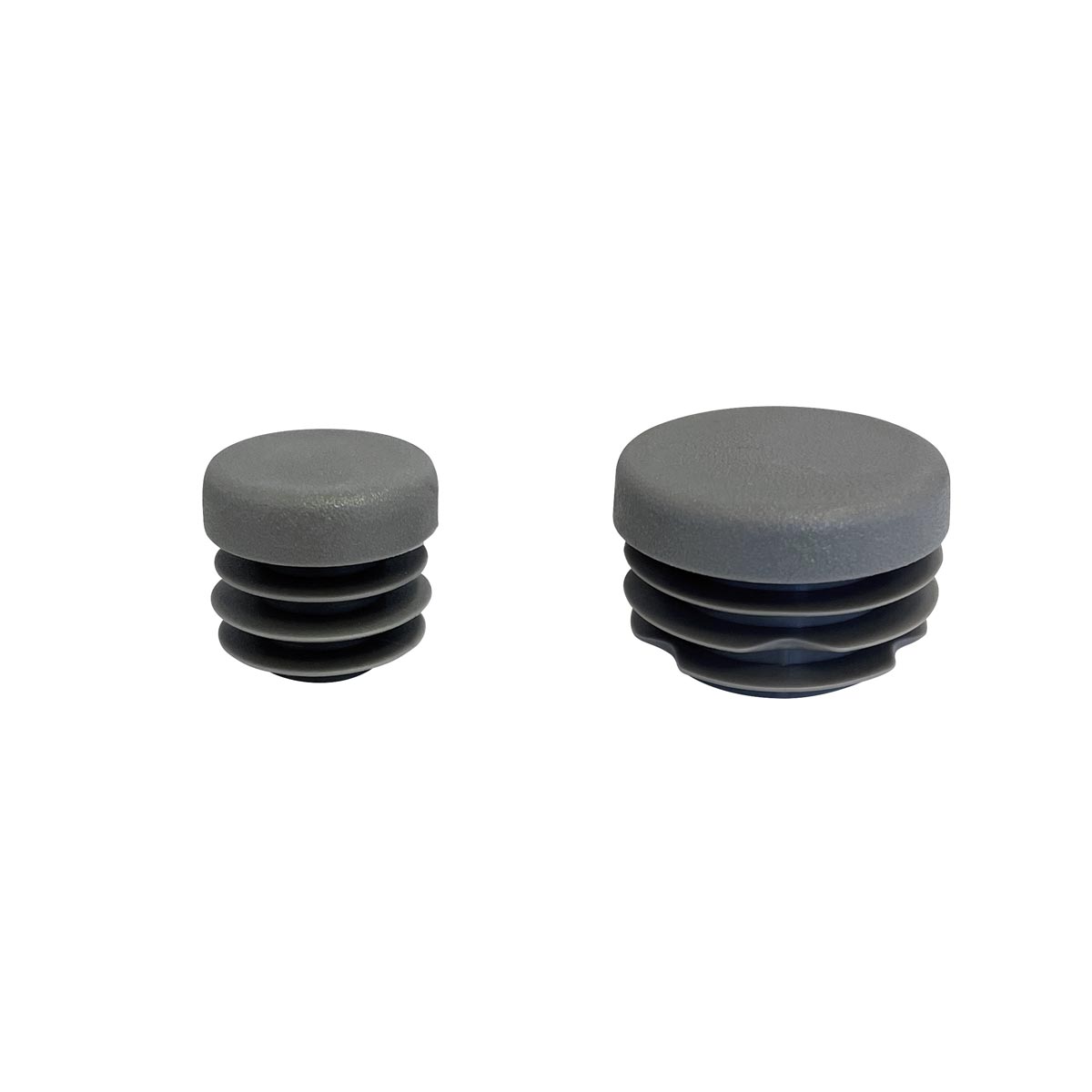 Größenvergleich der grauen Abschluss-Stopfen für 1/2" und 3/4" Eisenvermessungsrohre nebeneinander.