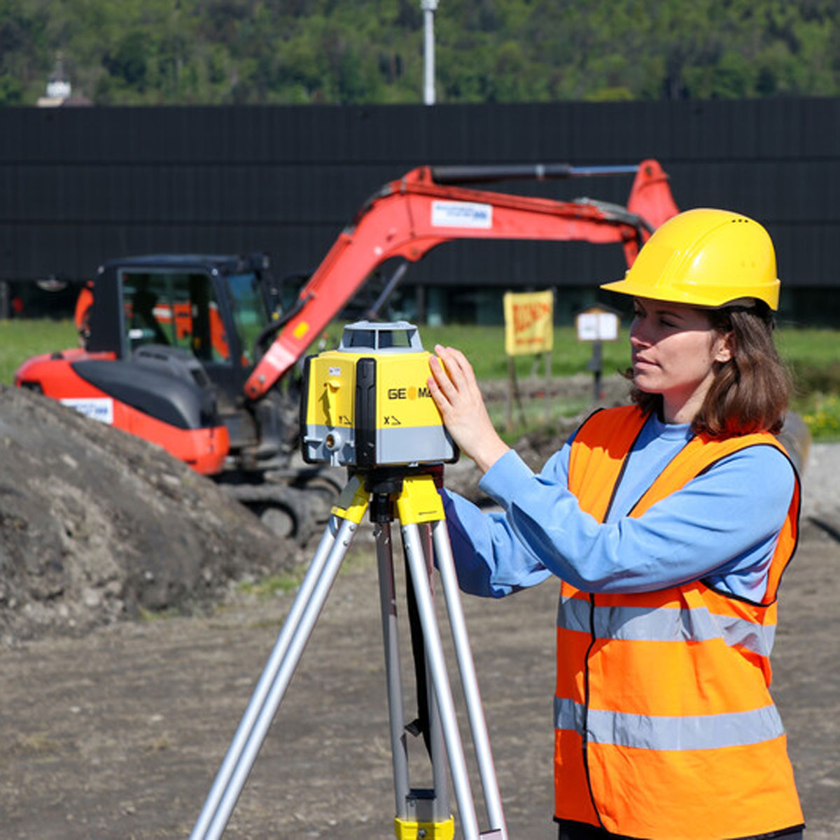 Eine Frau in Warnweste stellt den Neigungslaser von GeoMax vor einem Bagger im Tiefbau ein.