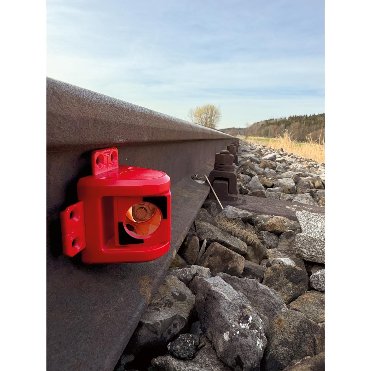 Rotes RSMP380 Prisma für die Gleisüberwachung, magnetisch an der Seite einer Bahnschiene befestigt.