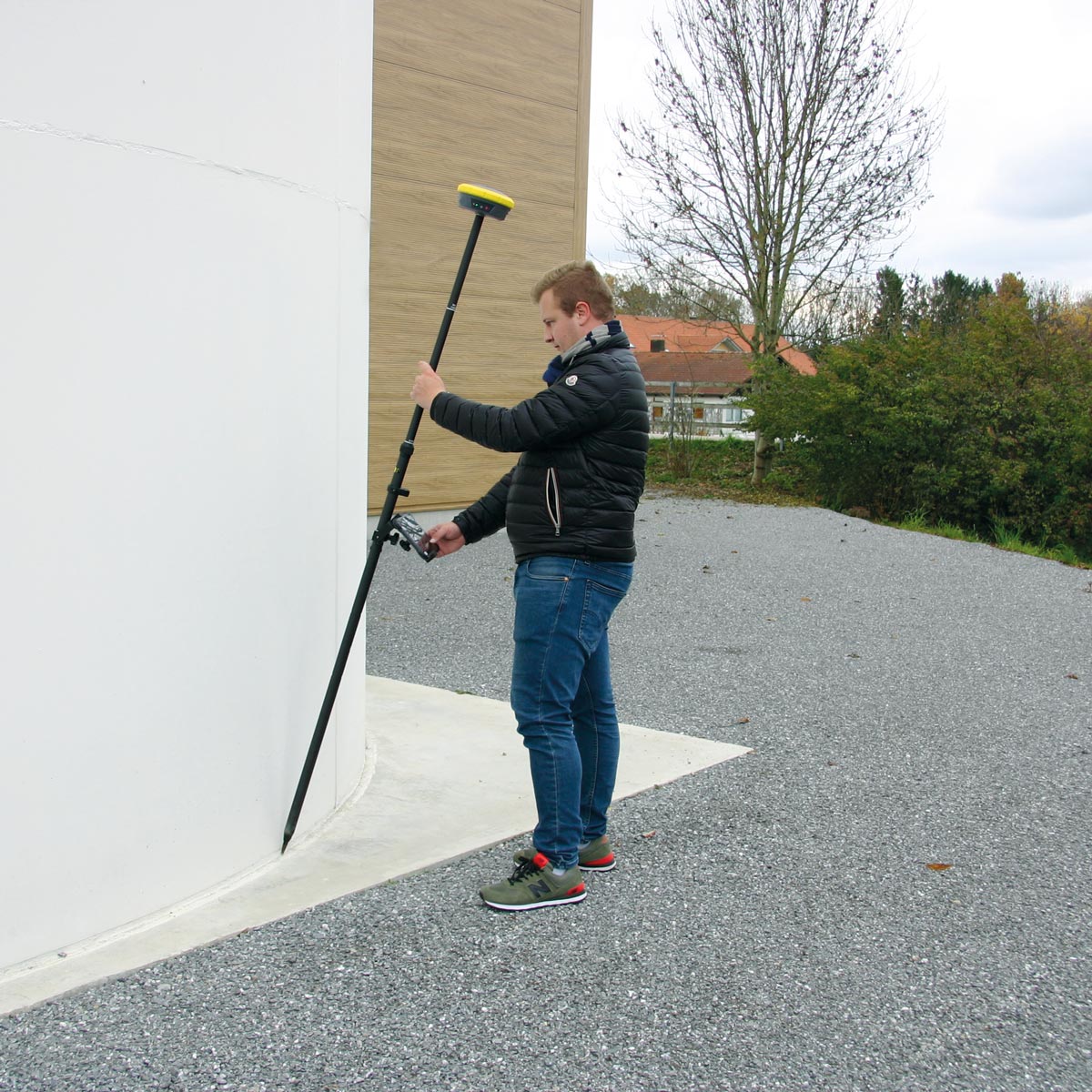 Vermesser misst mit geneigtem Lotstab und GeoMax Zenith60 einen Punkt an einer Gebäudeecke.