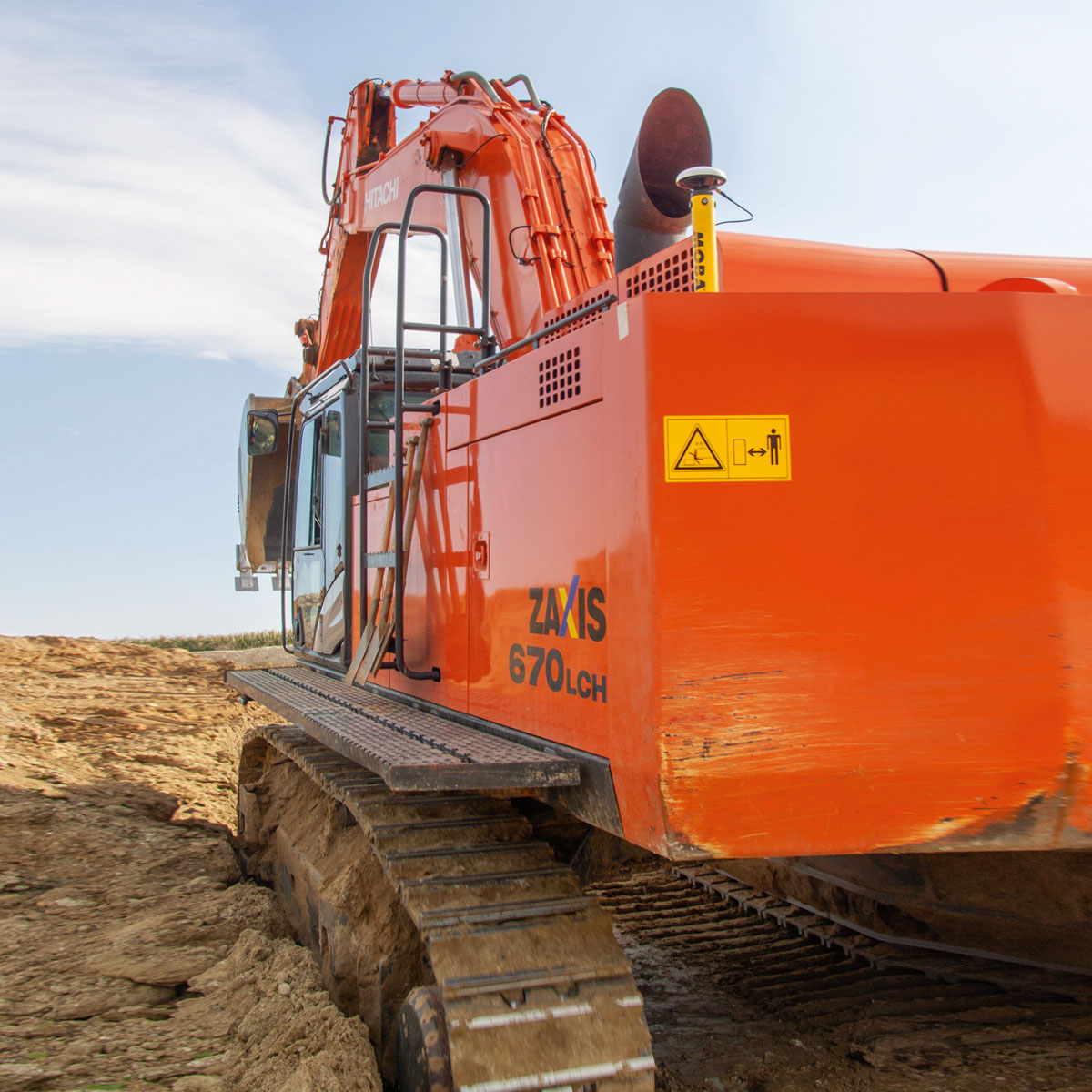 Hitachi Bagger Zaxis 670LCH mit gelbem MOBA-Antennenmast in einer Baugrube.
