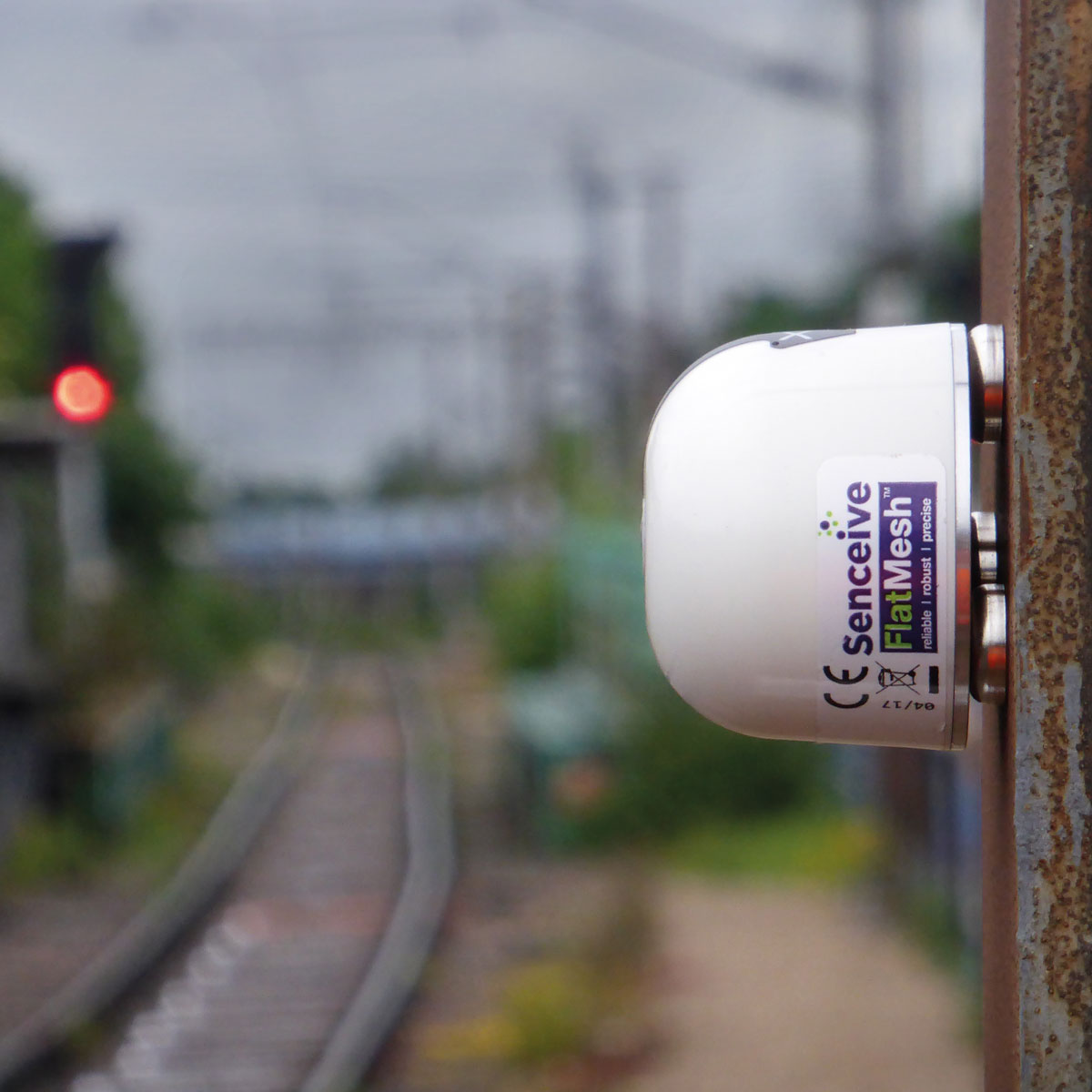 Der NanoPlus Neigungssensor ist seitlich an einem Metallpfahl an einer Bahnstrecke montiert.