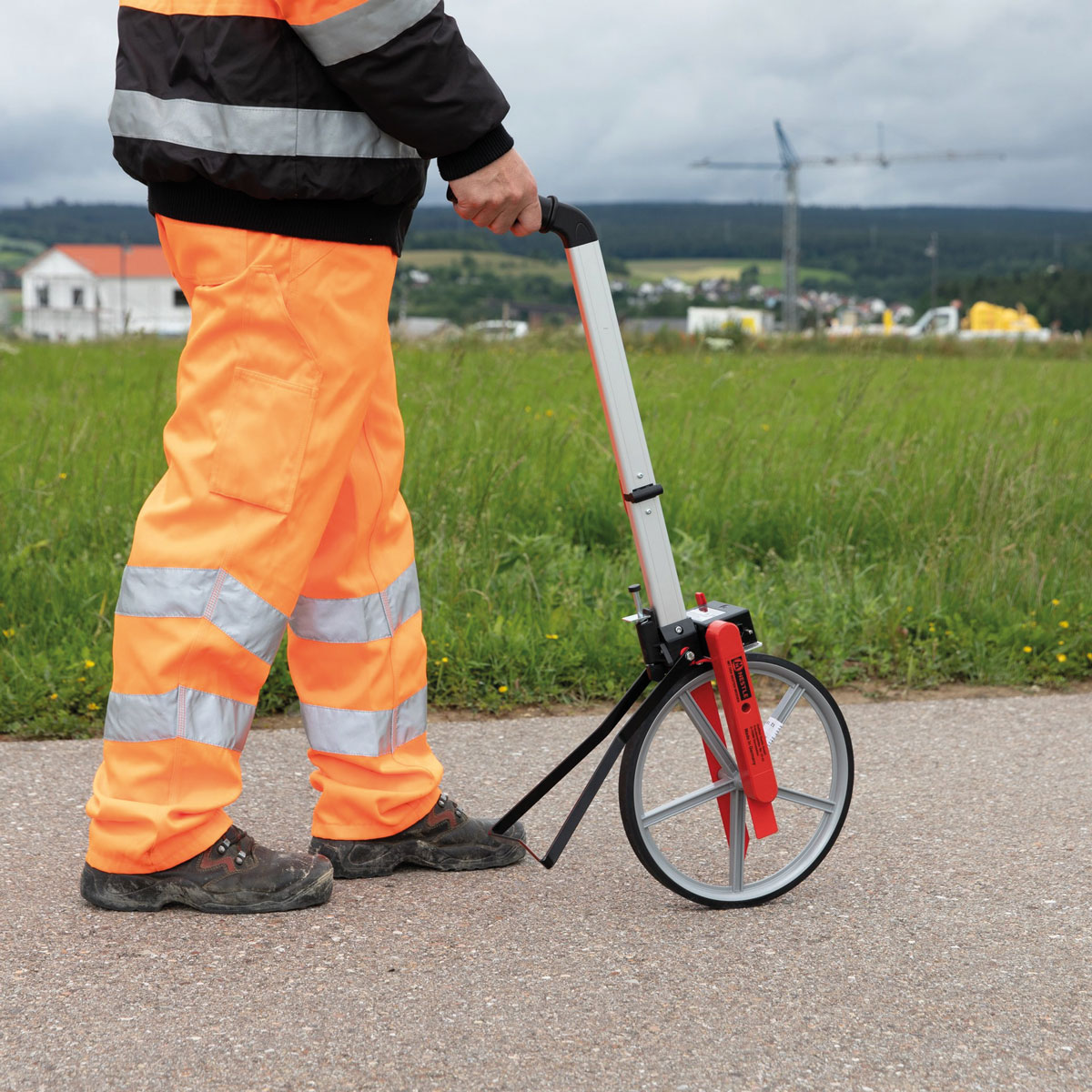Messrad MR-21 im Einsatz auf Straße Person in Warnkleidung benutzt das Messrad MR-21 auf Asphalt für präzise Messungen