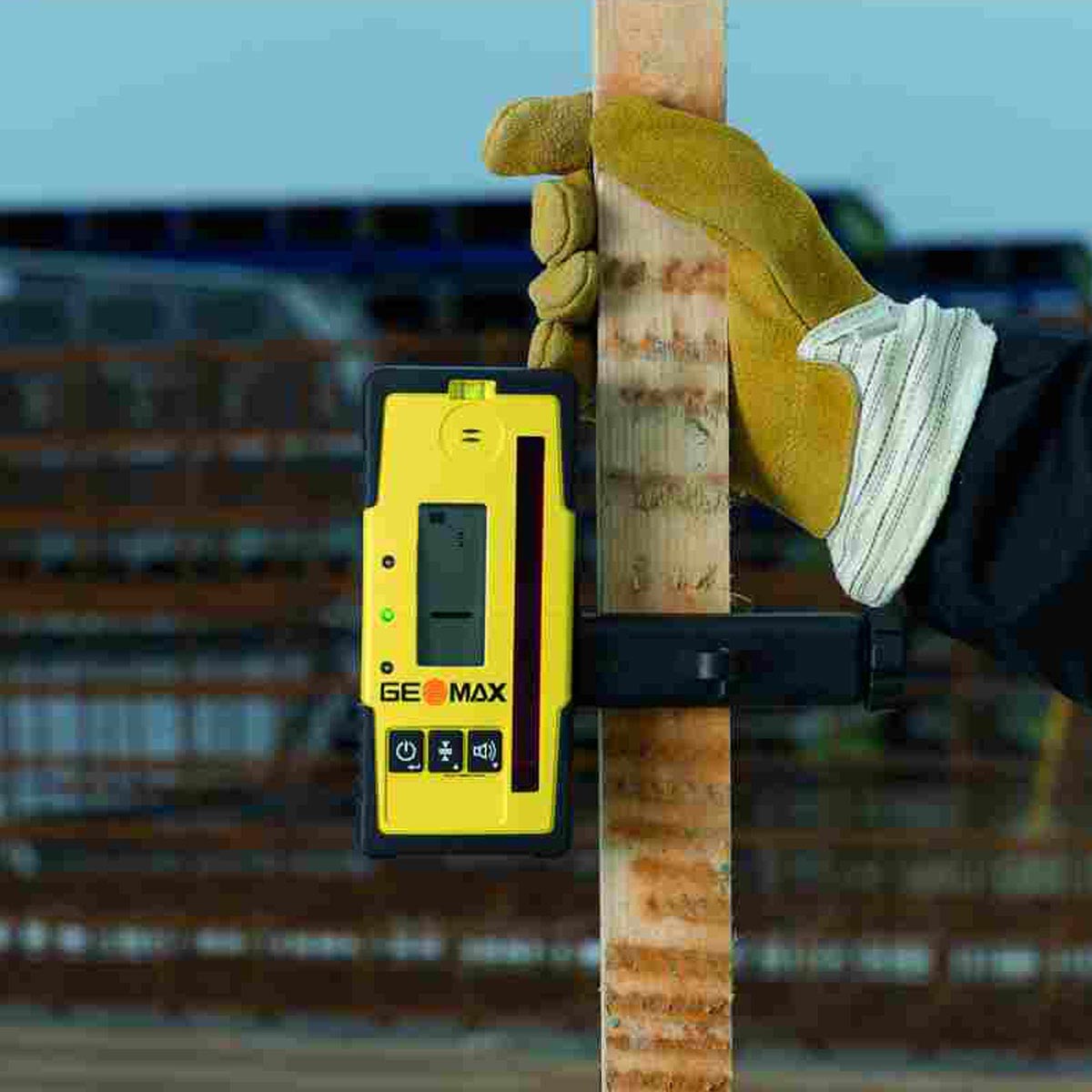 Hand mit Arbeitshandschuh hält eine Holzlatte mit montiertem GeoMax Handempfänger.