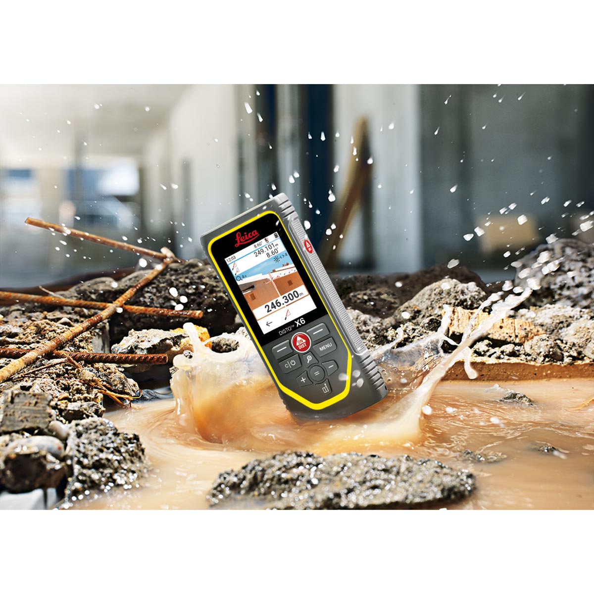 Leica Disto X6 liegt in einer schlammigen Pfütze auf der Baustelle, Wasser spritzt auf, robust und wasserdicht.