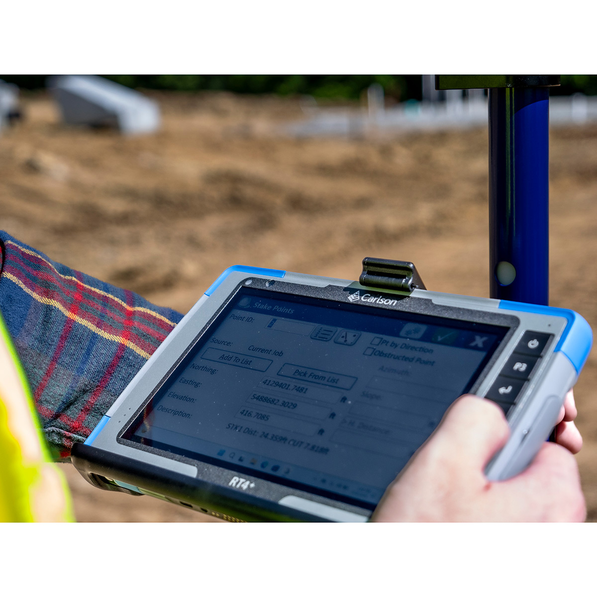 Vermessungsingenieur bedient das Carlson RT4+ Outdoor Tablet direkt im Feldeinsatz auf der Baustelle.