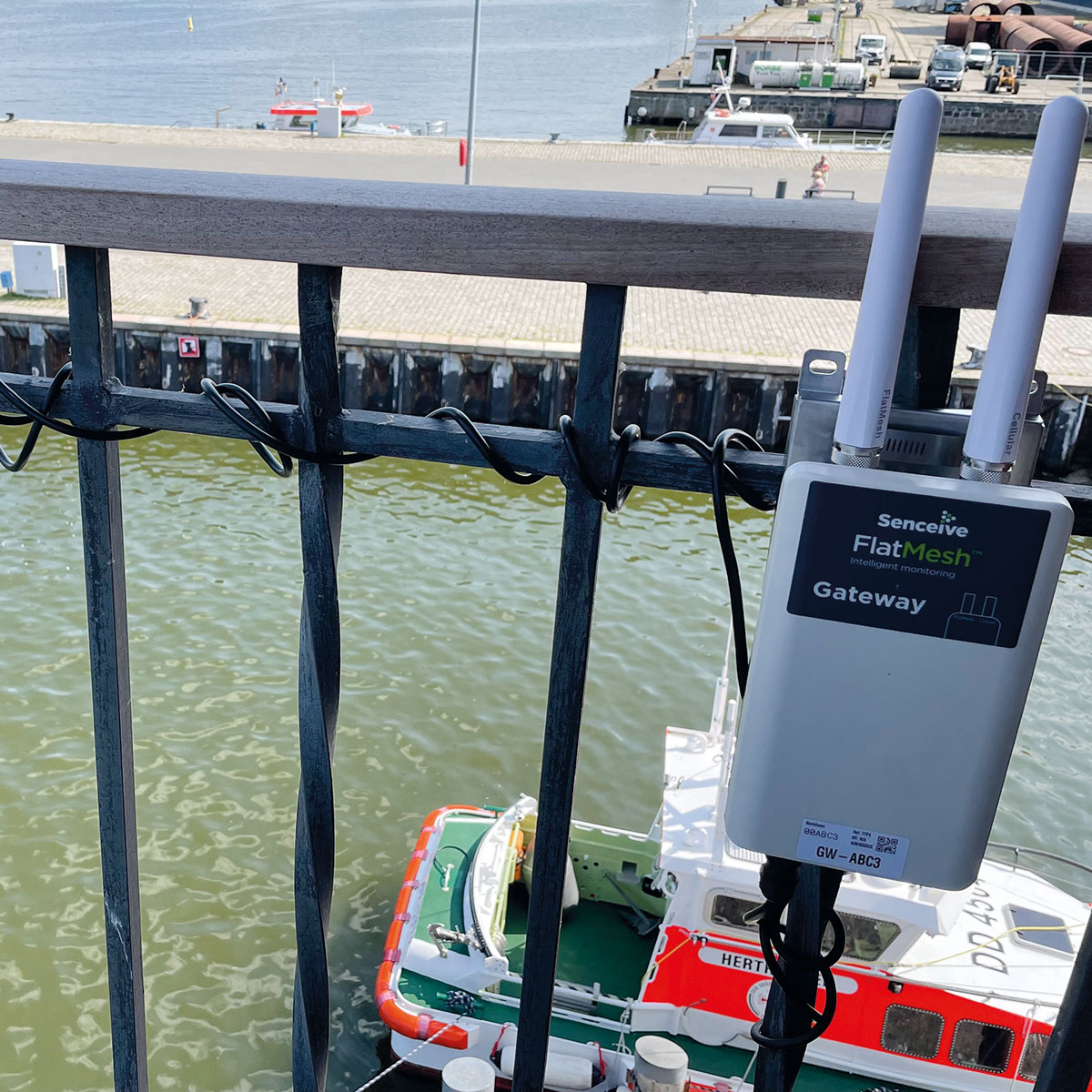 Das Senceive FlatMesh 4G Gateway zur Datenübertragung, montiert an einem Brückengeländer über dem Wasser.