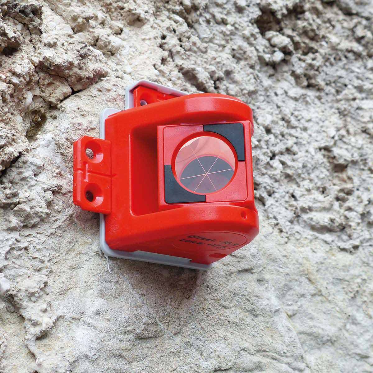 Das kleine, rote 180°-Prisma von Rothbucher ist unauffällig an einer Steinmauer befestigt.