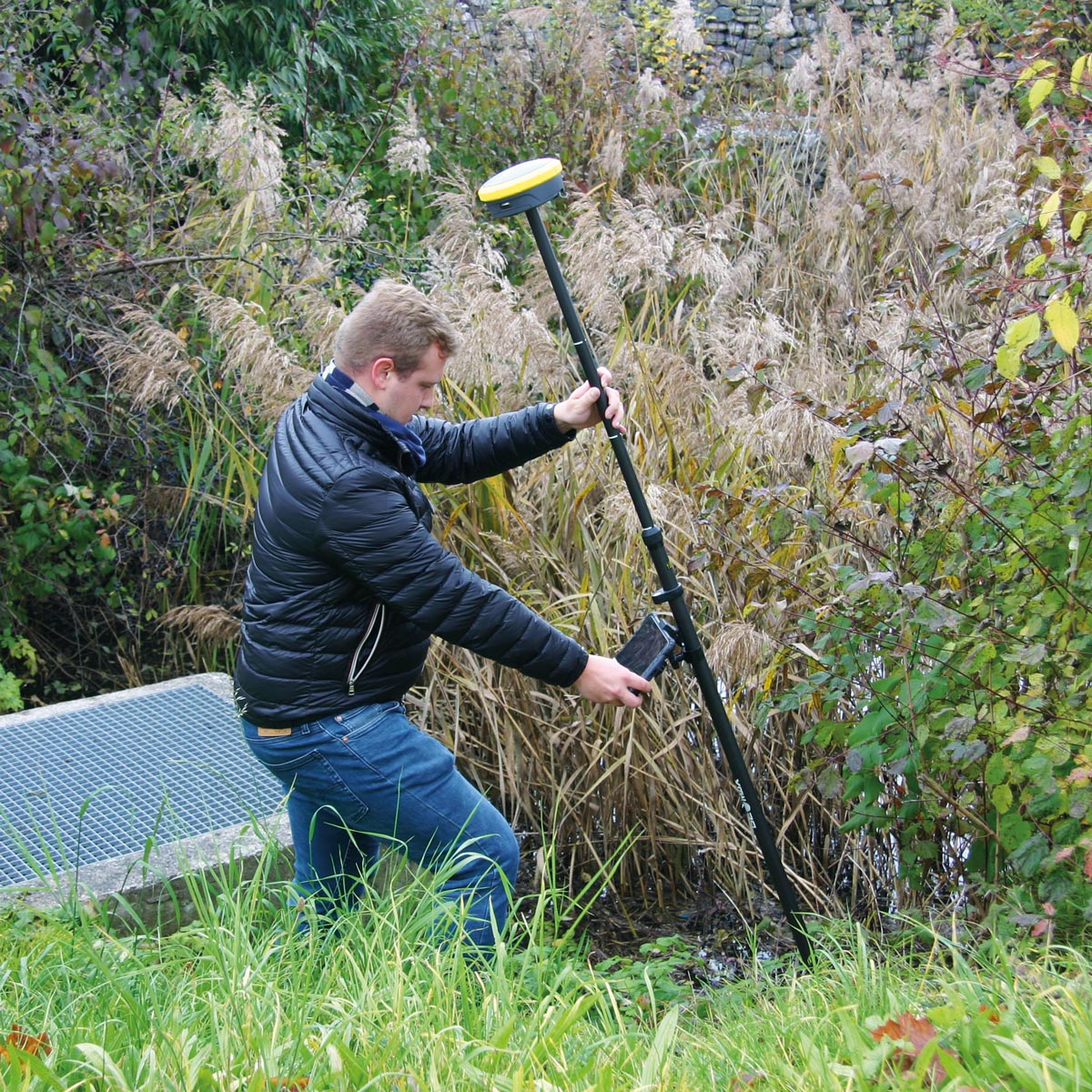 Vermesser misst mit dem GeoMax Zenith60 und geneigtem Lotstab im dichten Schilf.